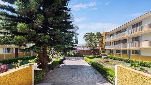 Un sendero que lleva a un edificio con fachada amarilla y varios balcones.