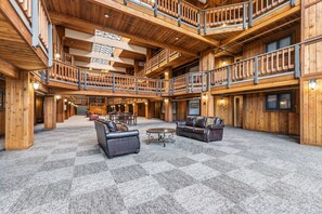 Eine großzügige Lobby mit Schachbrettmuster-Teppich, Holzwänden und einer zentralen Sitzecke mit Sofas und einem Couchtisch.