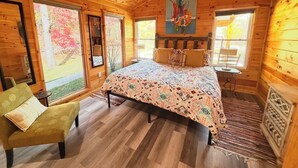 Une chambre chaleureuse dans un chalet en rondins, avec un lit, une chaise et un tableau accroché au mur.