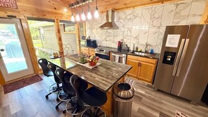 Une cuisine moderne dotée d’un îlot central en bois, d’appareils électroménagers en acier inoxydable et d’un dosseret en marbre.