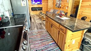 Une cuisine moderne avec des murs en bois, un poêle noir et un tapis coloré.