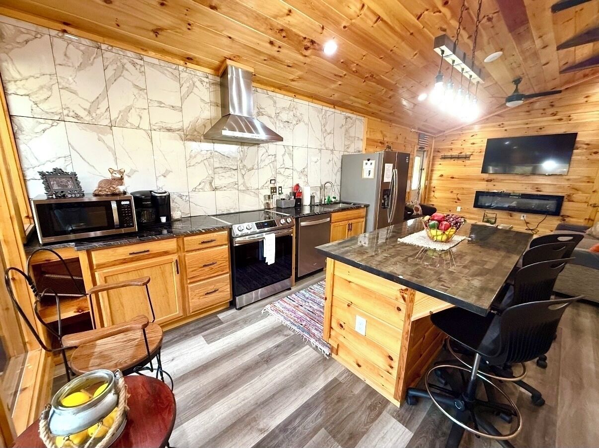 A modern kitchen with wooden cabinets, a central island, and built-in appliances.