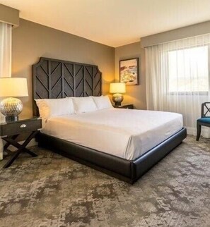 A hotel room with a large bed, a headboard, a nightstand, a lamp, and a window with curtains. - Stunning Oceanfront | Aston Waikiki Beach Tower 2BOF2 – Pool, Hot Tub & Spa (Honolulu)