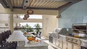 An outdoor kitchen area with a stone island, grilling station, and dining chairs.