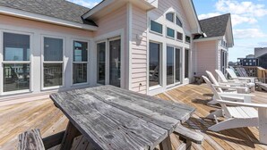 Een huis aan de kust met een terras, buitenzitplaatsen en grote ramen.