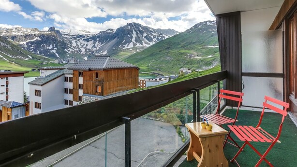 Un balcón con vistas a montañas y una pequeña mesa con sillas.