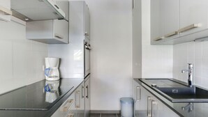 Una cocina moderna con cafetera, un cesto de basura y un lavamanos.