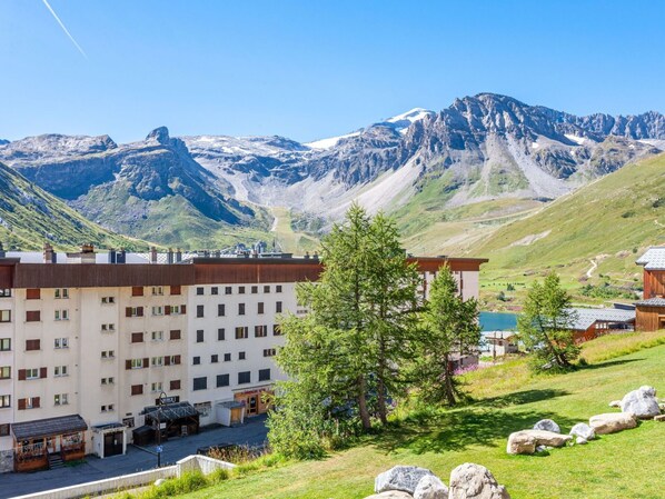 A hotel with multiple floors, a parking area, and a view of mountains.