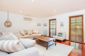 Een woonkamer met een bank, fauteuils, een salontafel en een hanglamp.