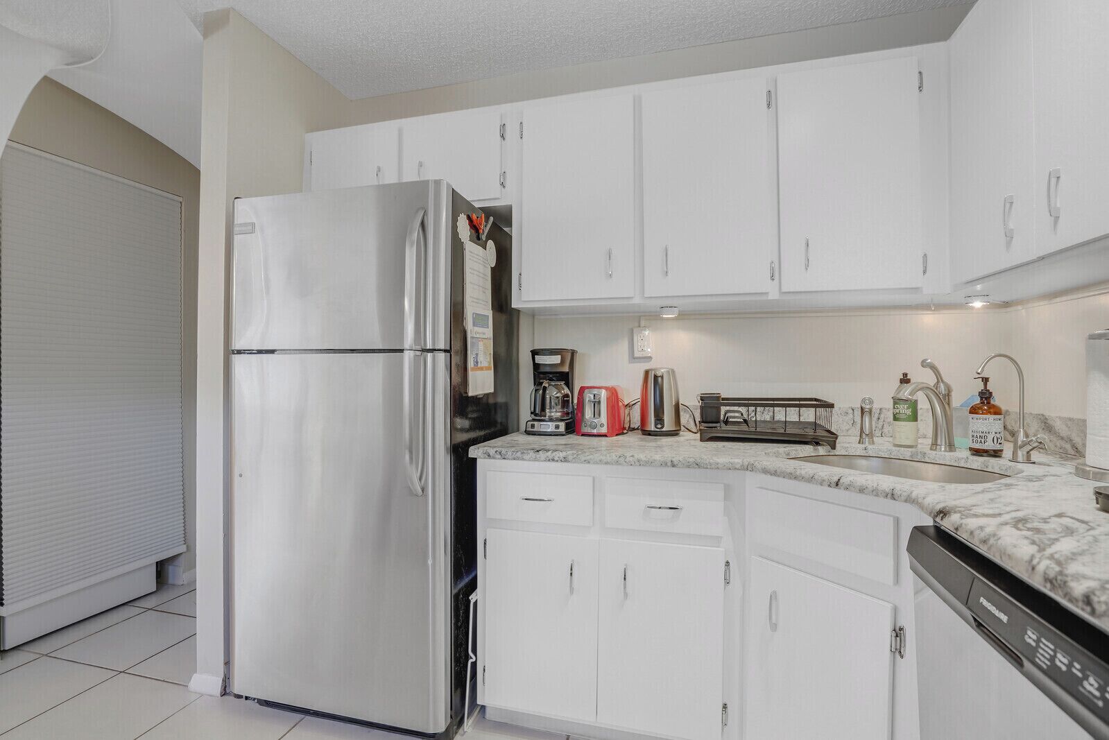 A modern kitchen with white cabinets, stainless steel appliances, and a dishwasher.