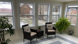A sunroom with two wicker chairs, a small table, and a potted plant.