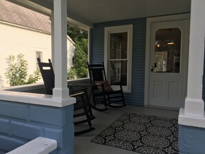 A porch with a rocking chair and a table, a patterned rug, and a white door. - charming 3 bedroom house in quiet neighborhood 3 miles to horse show by the bay  (Williamsburg)