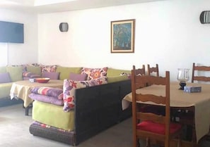 Une pièce confortable avec un canapé, une table à manger et un tableau accroché au mur.