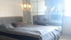A bedroom with a bed, a headboard, a nightstand, and a wall-mounted light fixture. - Residence Tamourrit Taghazout Bay 4747 (Taghazout)