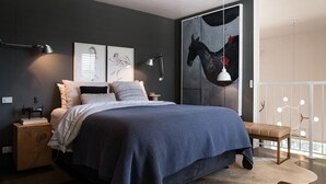 A modern bedroom with a large bed, bedside tables, a bench, and artwork on the walls. - Harts Lane Stag and Millies- sleek design and pet friendly (Daylesford)
