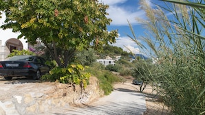 Un sendero pavimentado junto a un edificio con muro de piedra y vegetación.