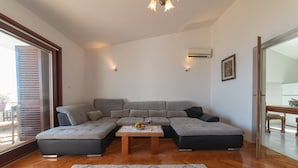 Una sala de estar moderna con un sofá seccional, una mesa de centro de madera y un ventanal con persianas.