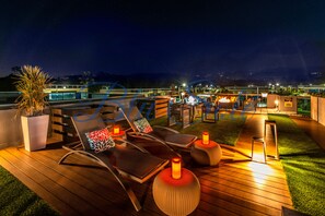 Relax on the tranquil outdoor space with lounge chairs and a scenic view of the water and distant hills.