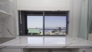 A modern kitchen with a marble countertop and a view of the sea through a large window. - UNIT 2  OPPOSITE BEACH, RIVER ,HOTEL,CLUB,WALKING DISTANCE TO ALL VENUES ETC..
 (HARRINGTON)