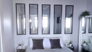 A bedroom with a bed, bedside tables, a ceiling fan, and a large mirror on the wall. - UNIT 2  OPPOSITE BEACH, RIVER ,HOTEL,CLUB,WALKING DISTANCE TO ALL VENUES ETC..
 (HARRINGTON)