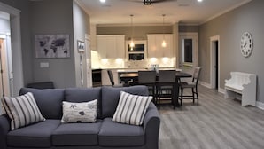 Una sala de estar moderna con un sofá gris, almohadones a rayas y piso de madera.