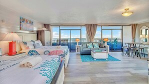 A spacious living area with a large bed, a sofa, a coffee table, and a dining table. There are large windows offering a view of the ocean. - WOW CORNER ALL GLASS PARLOR UNIT/60 FOOT OF BALCONY/2 BALCONIES (Myrtle Beach)