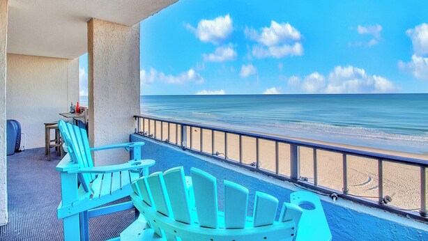 A balcony with turquoise Adirondack chairs, a small table, and a view of the ocean. - WOW CORNER ALL GLASS PARLOR UNIT/60 FOOT OF BALCONY/2 BALCONIES (Myrtle Beach)