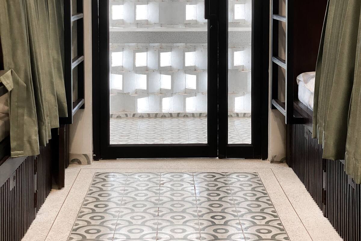A room with a patterned floor, a black door with frosted glass panels, and green curtains on the sides.