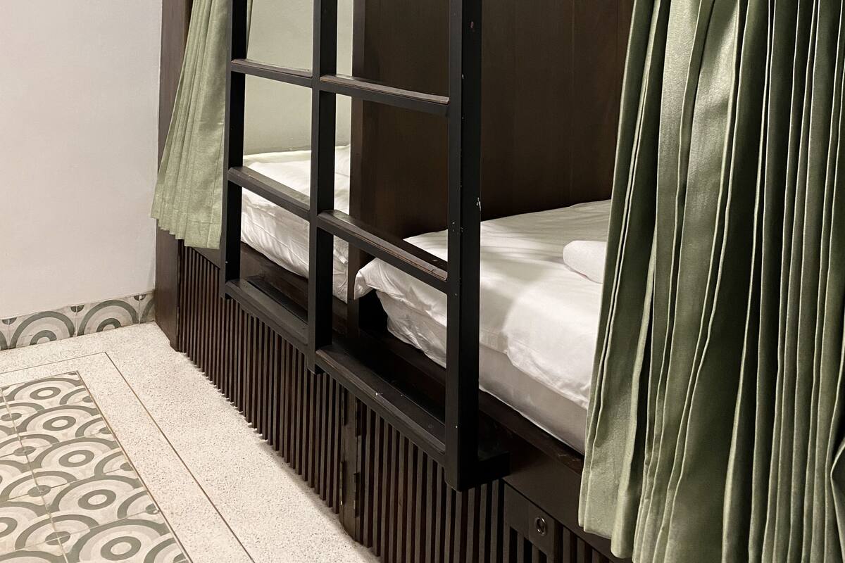 A bunk bed with a wooden frame and green curtains.