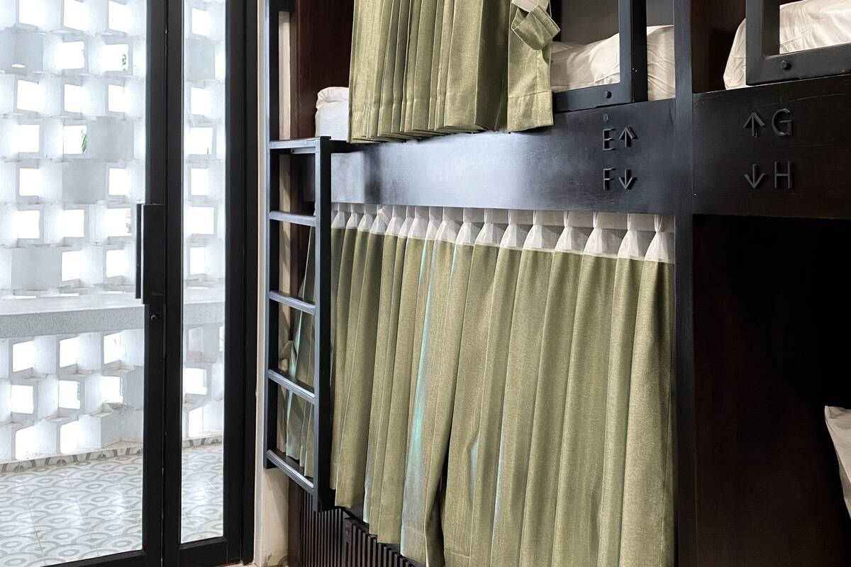 A hotel room with a bunk bed, a sliding door leading to a balcony, and a patterned floor.