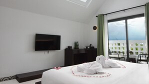 Une chambre d’hôtel équipée d’un lit, d’une télévision à écran plat, d’un bureau et d’un balcon avec vue.