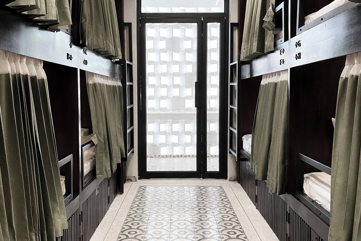 A hallway with bunk beds, a patterned floor, and a door with a geometric window design.