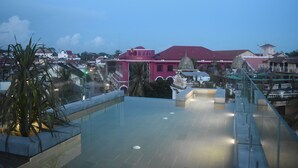 Une terrasse sur le toit offrant une vue dégagée sur les bâtiments environnants, dont un imposant édifice de couleur rose.