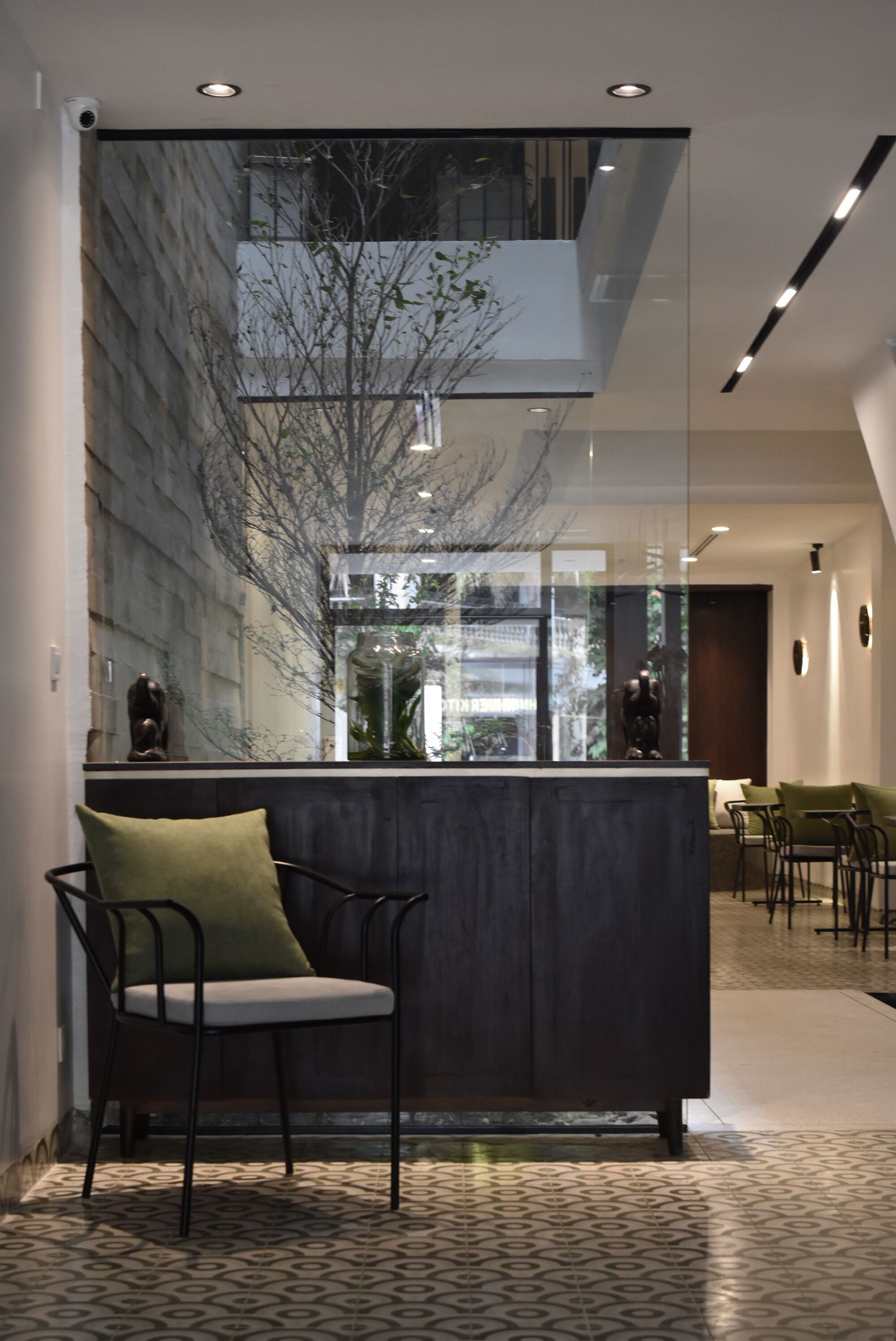 A modern reception area with a glass partition, a reception desk, and a seating area with chairs and a sofa.