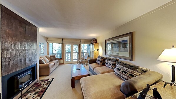 A living room with a fireplace, sofas, a coffee table, and a lamp.