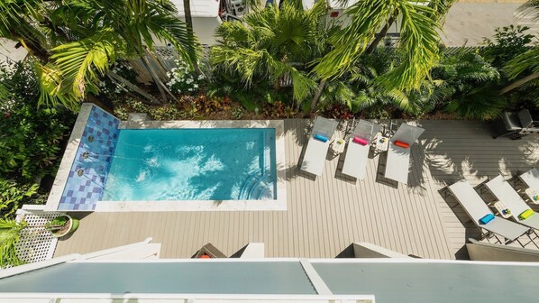 Piscina al aire libre con tumbonas y palmeras.