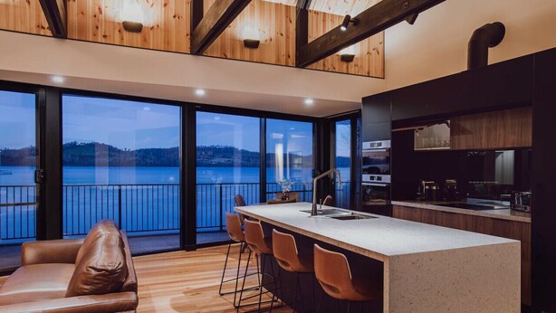 A modern kitchen with a large island, bar stools, and a view of a body of water. - Deviot Boat House - romantic, absolute waterfront (Deviot)