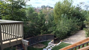 Eine Terrasse mit einem Steinweg, der zu einer von Bäumen umgebenen Rasenfläche führt.