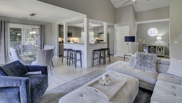 A spacious living area with a large sofa, a dining table with chairs, and a kitchen area with a bar. - Sunset Rentals | Evian 233 (Hilton Head Island)
