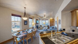 A spacious kitchen with granite countertops, wooden cabinets, and a dining area with a table set for four. - Foxpoint 2 Bedroom Condo by RedAwning (Park City)