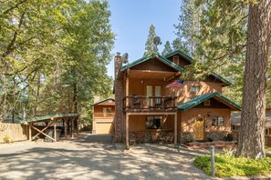 Eine zweistöckige Lodge mit Balkon, überdachter Veranda und einem Steinfundament.
