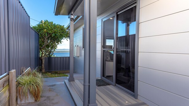 A modern house with a covered porch, large sliding glass doors, and a view of the ocean. - UNIT   1.. OPPOSITE THE OCEAN.. BEACH ..RIVER..PET FRIENDLY. 1 FREE PARKING  
 
 (HARRINGTON)