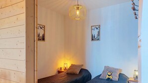 A room with two beds, a hanging light fixture, and two wall-mounted picture frames. - Les Terrasses du Corbier by Interhome (Le Corbier)
