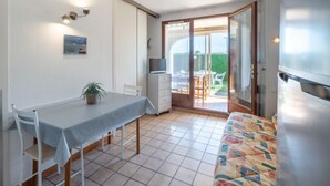 Ein gemütlicher Raum mit Esstisch, einer Couch, einem Fernseher und einer Glastür zu einem Außenbereich.