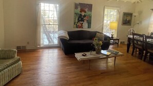 A spacious living room with a dark-colored sofa, a coffee table with a vase, and a dining area with chairs and a table. - Funky and Charming Home! (Laramie)