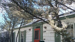 A small, single-story house with a red door, green shutters, and a mailbox. - Funky and Charming Home! (Laramie)