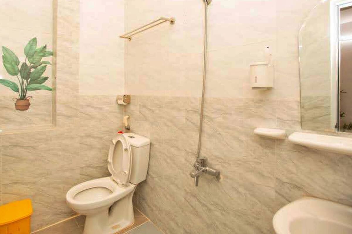 A bathroom with a toilet, a shower, a sink, and a mirror.