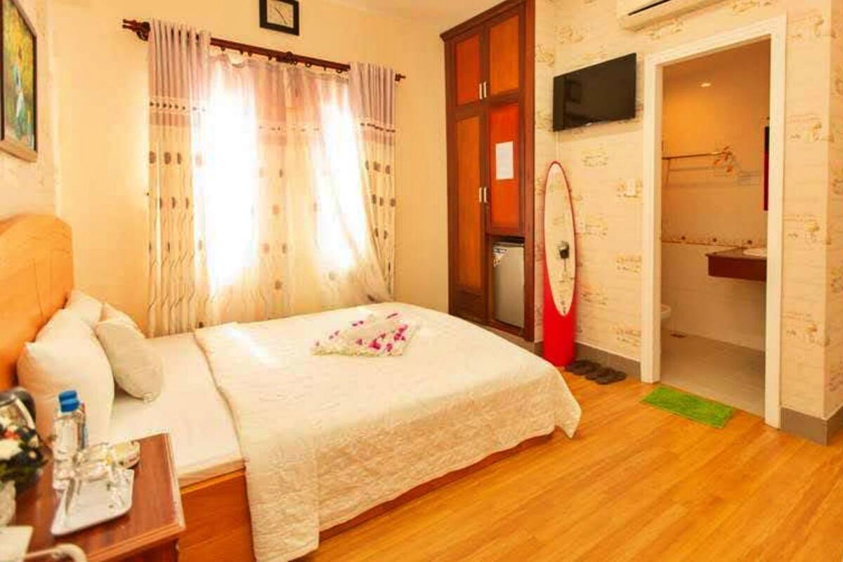 A hotel room with a bed, a desk with a lamp, a shower area, and a television mounted on the wall.