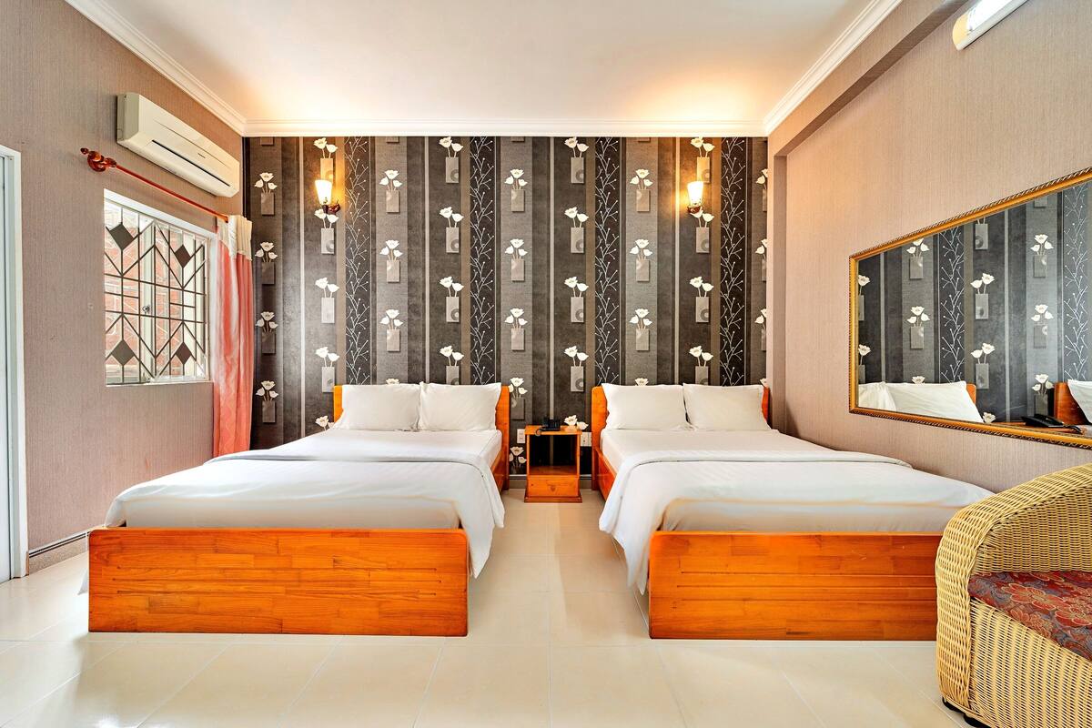 A hotel room with two beds, a large mirror, and a decorative wall.
