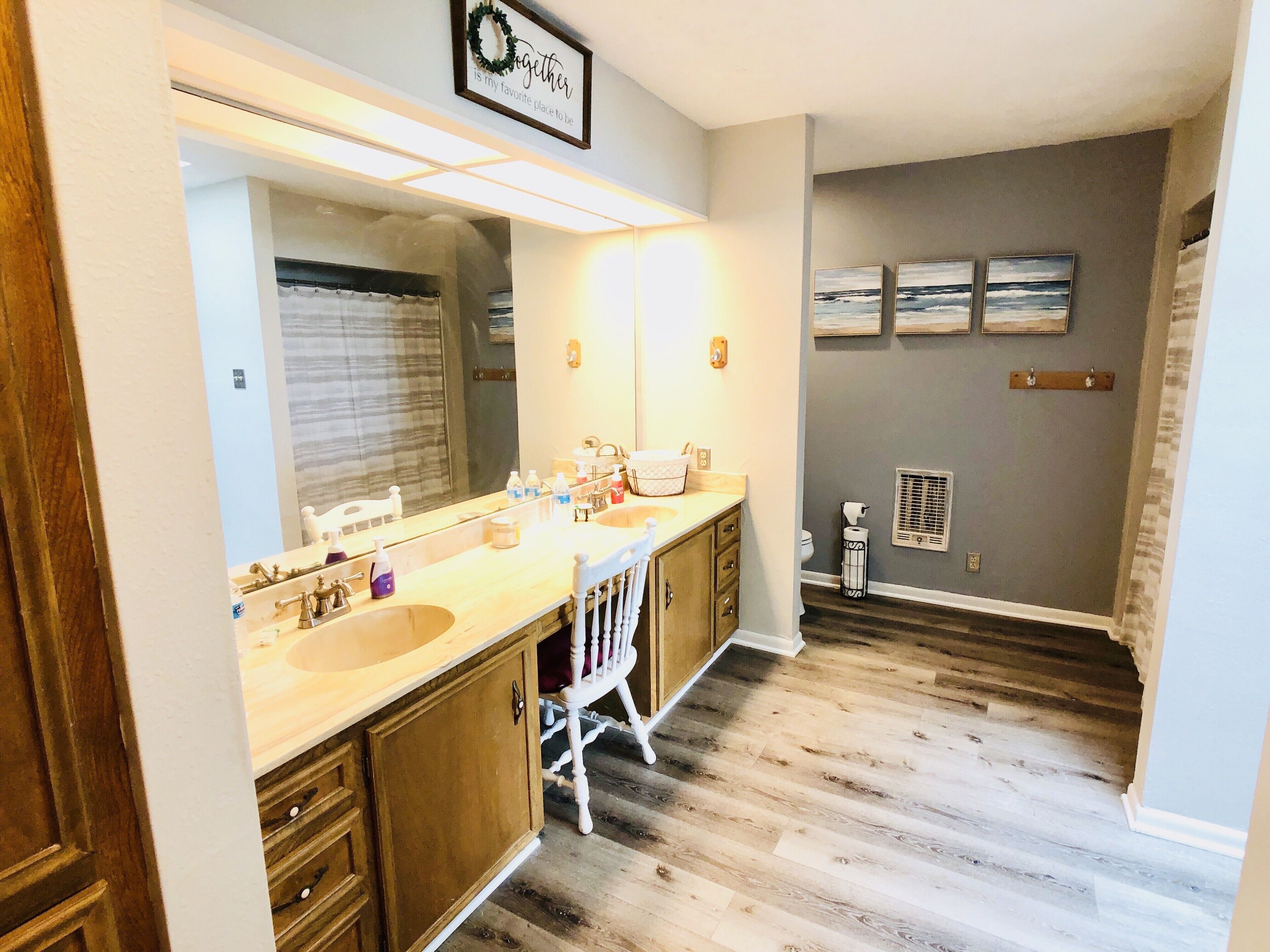 Une salle de bain avec un double lavabo, des meubles en bois, un grand miroir et un porte-serviettes fixé au mur.